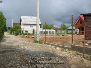 Фундамент забора у дороги. На переднем плане проем для ворот
