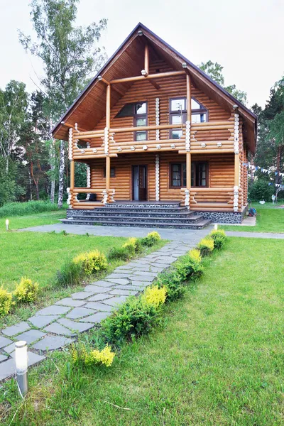 Большой деревянный дом из оцилиндрованного бревна возле леса Стоковое Изображение
