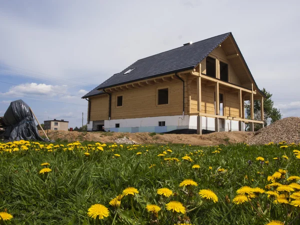 Строительство деревянного дома и жёлтые одуванчики на лугу Лицензионные Стоковые Изображения